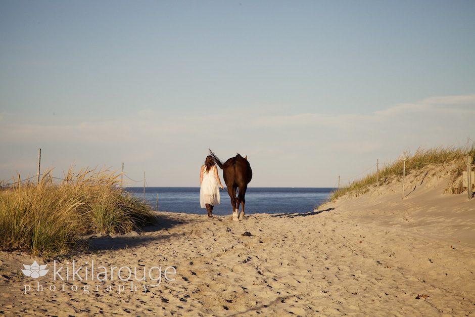 Girl on beach path with horse