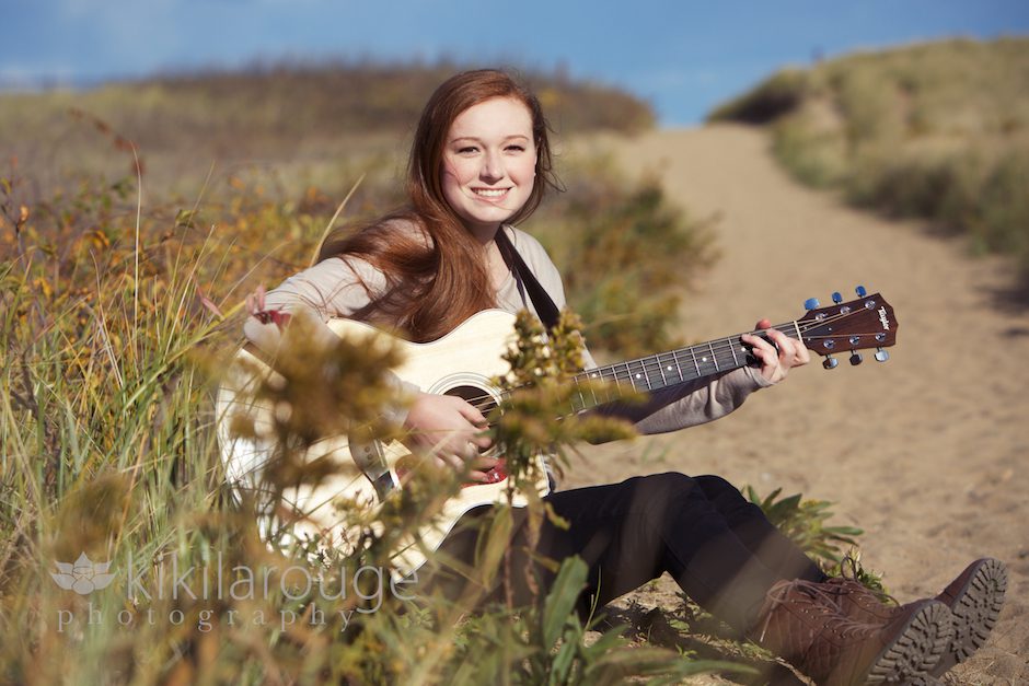 Redheaded girl playing guitar at beach