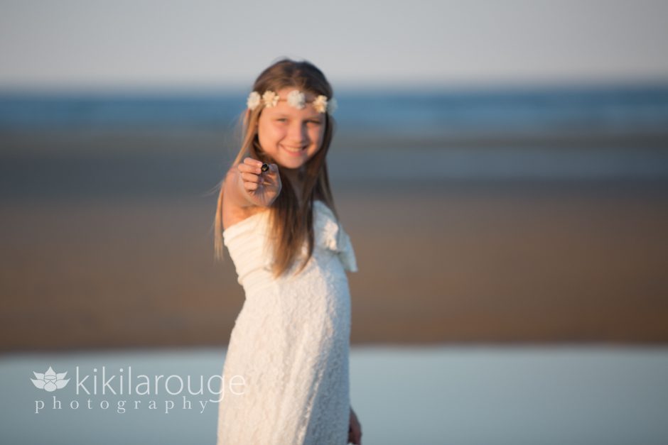 Girl in white dress on beach holding shell