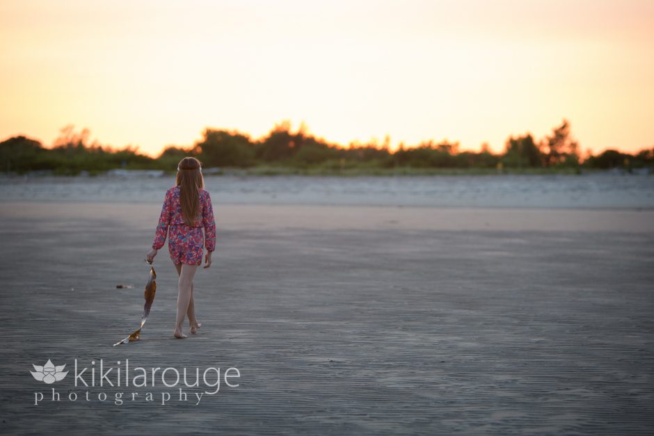 Girl walking with seaweed at sunset