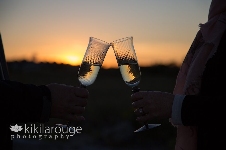 Two champagne glasses toasting at sunset