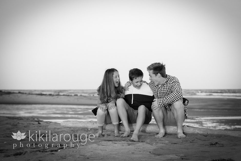 Kids laughing on piece of driftwood at beach
