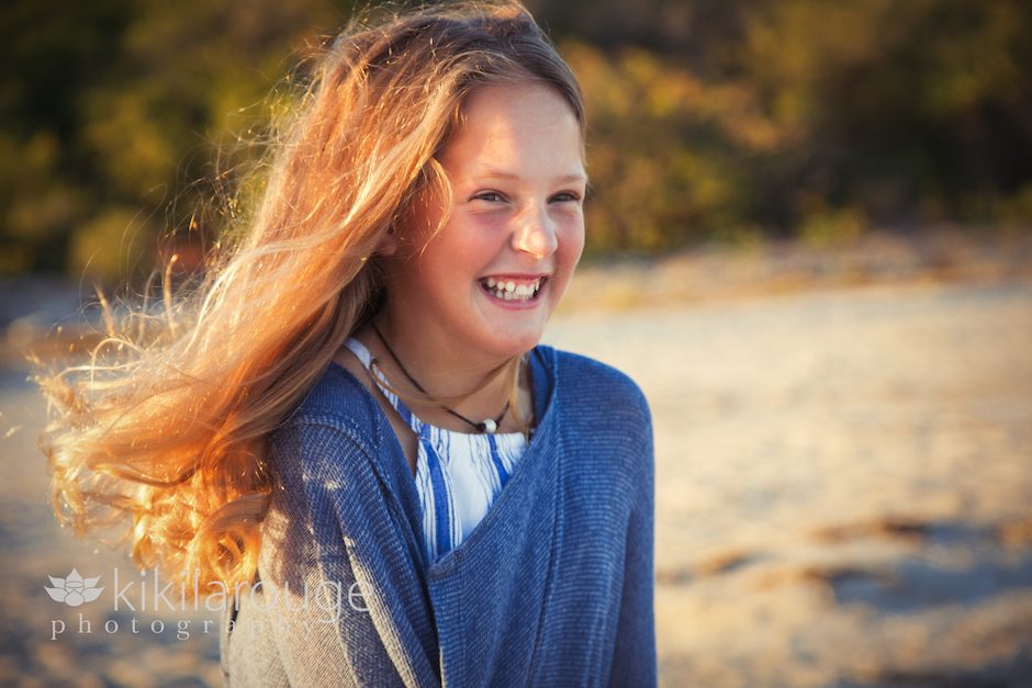 Young girl laughing at windy beach