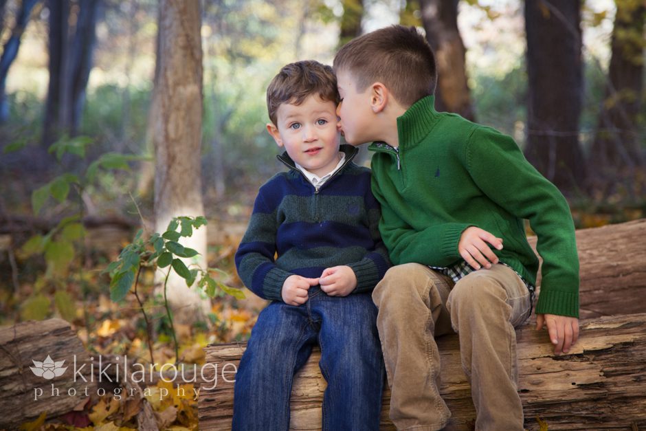 Two brothers sitting on log in forest