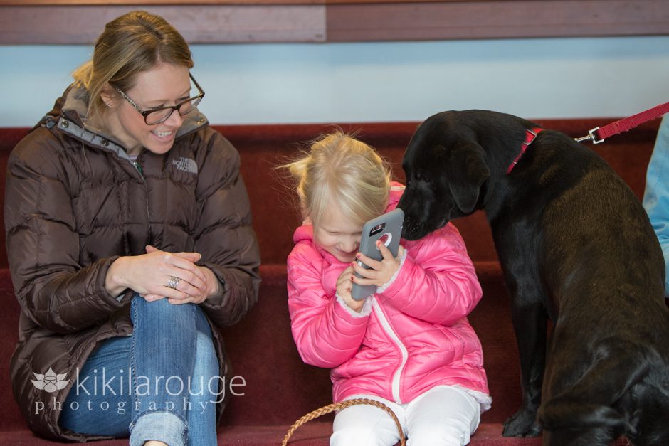 Black lab looking at little girls phone