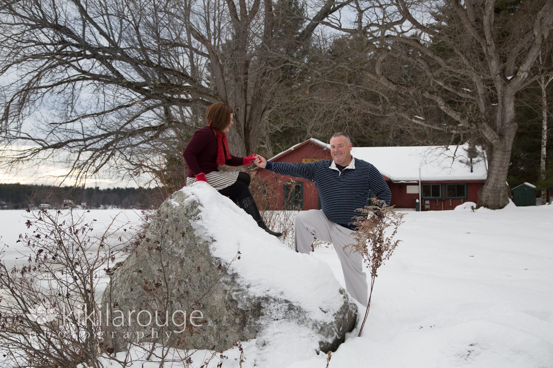 Man helping wife off snowy rock