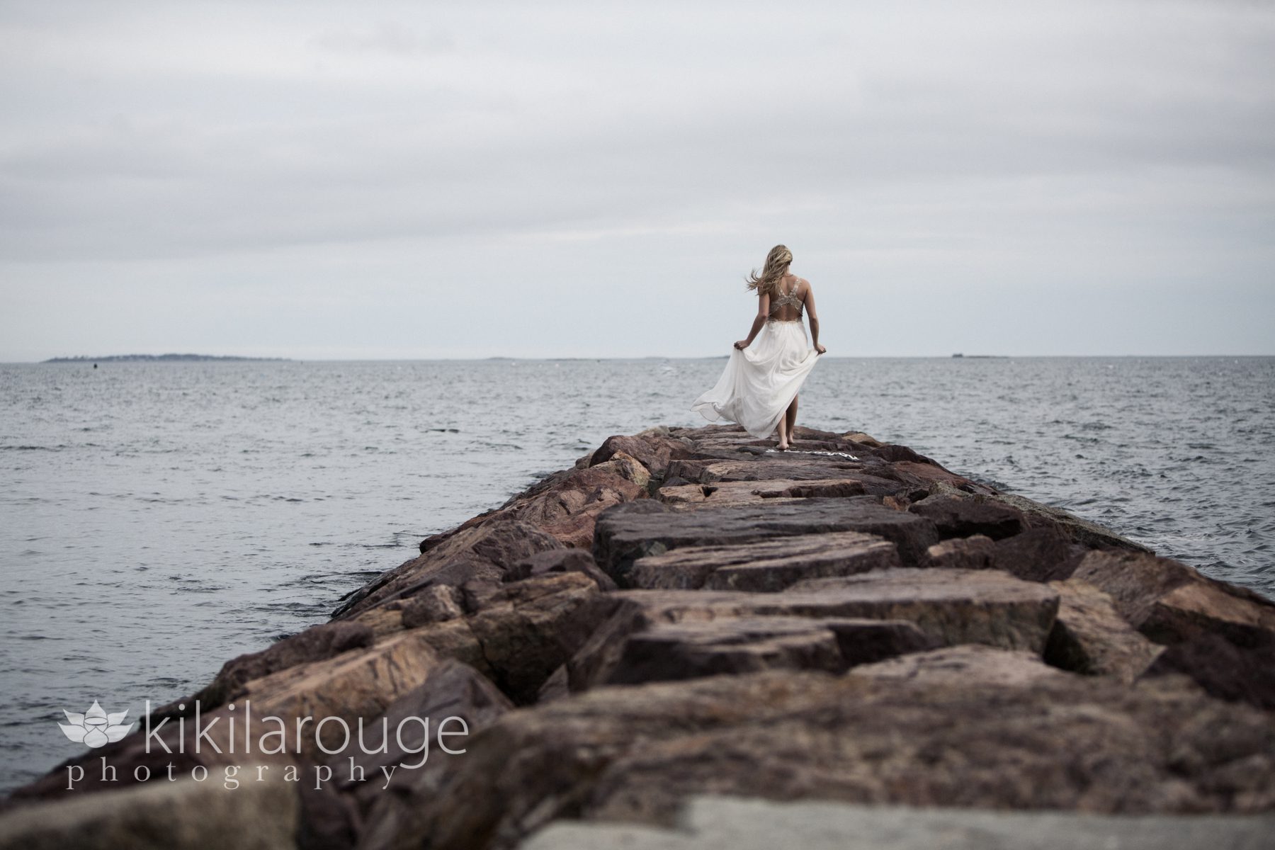 Girl walking away on jetty with prom dress