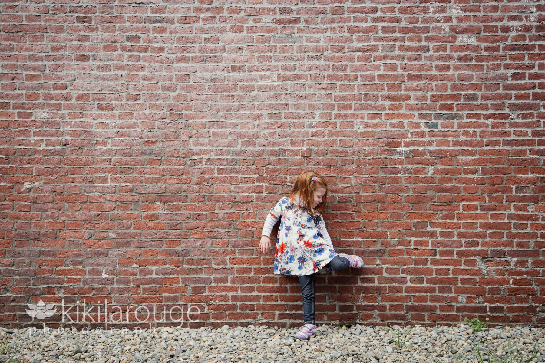 Little girl up against brick wall