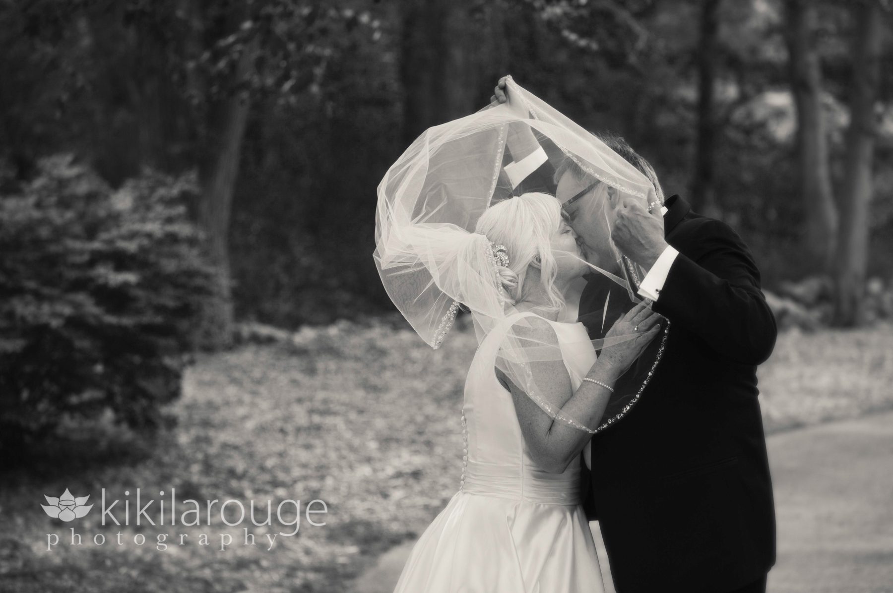 Couple under veil kissing in wind