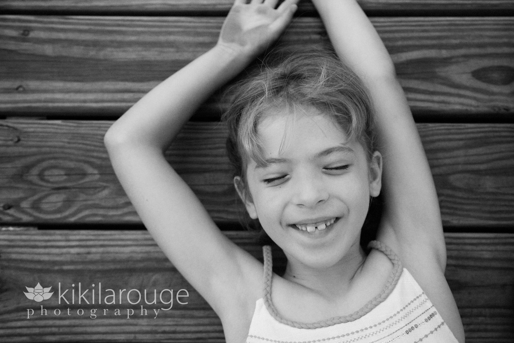 Little girl laying on dock smiling