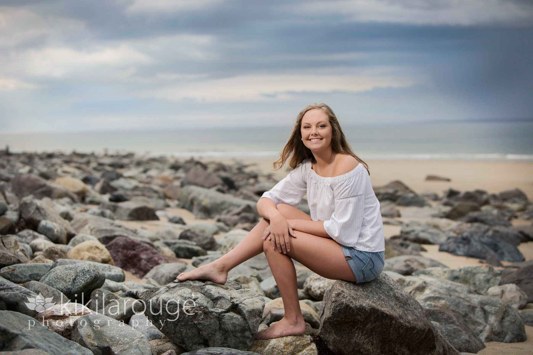 Senior girl sitting on rocks with storm
