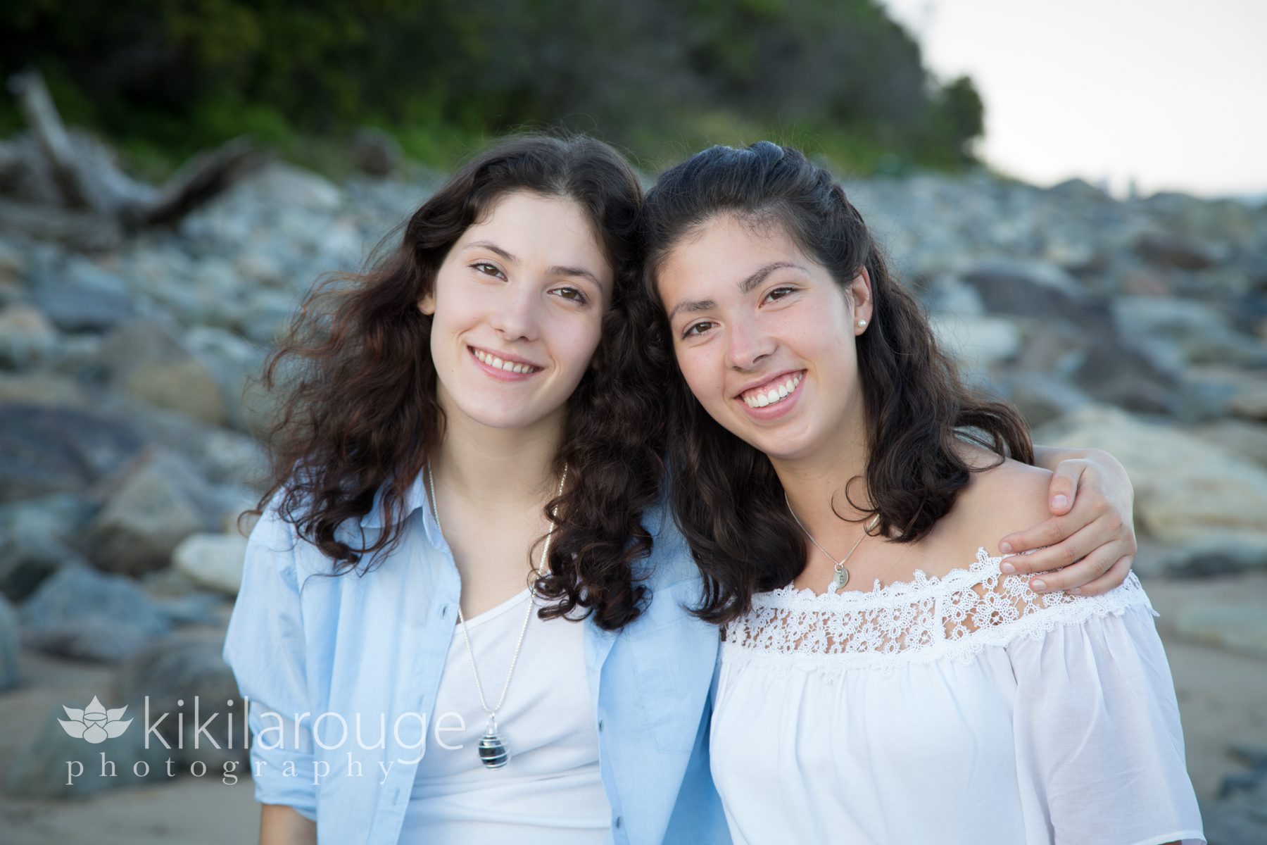 Twin girls senior portraits on rocks at beach