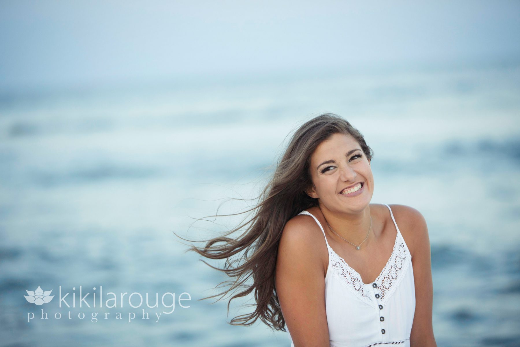 Girl white dress smiling all ocean backdrop