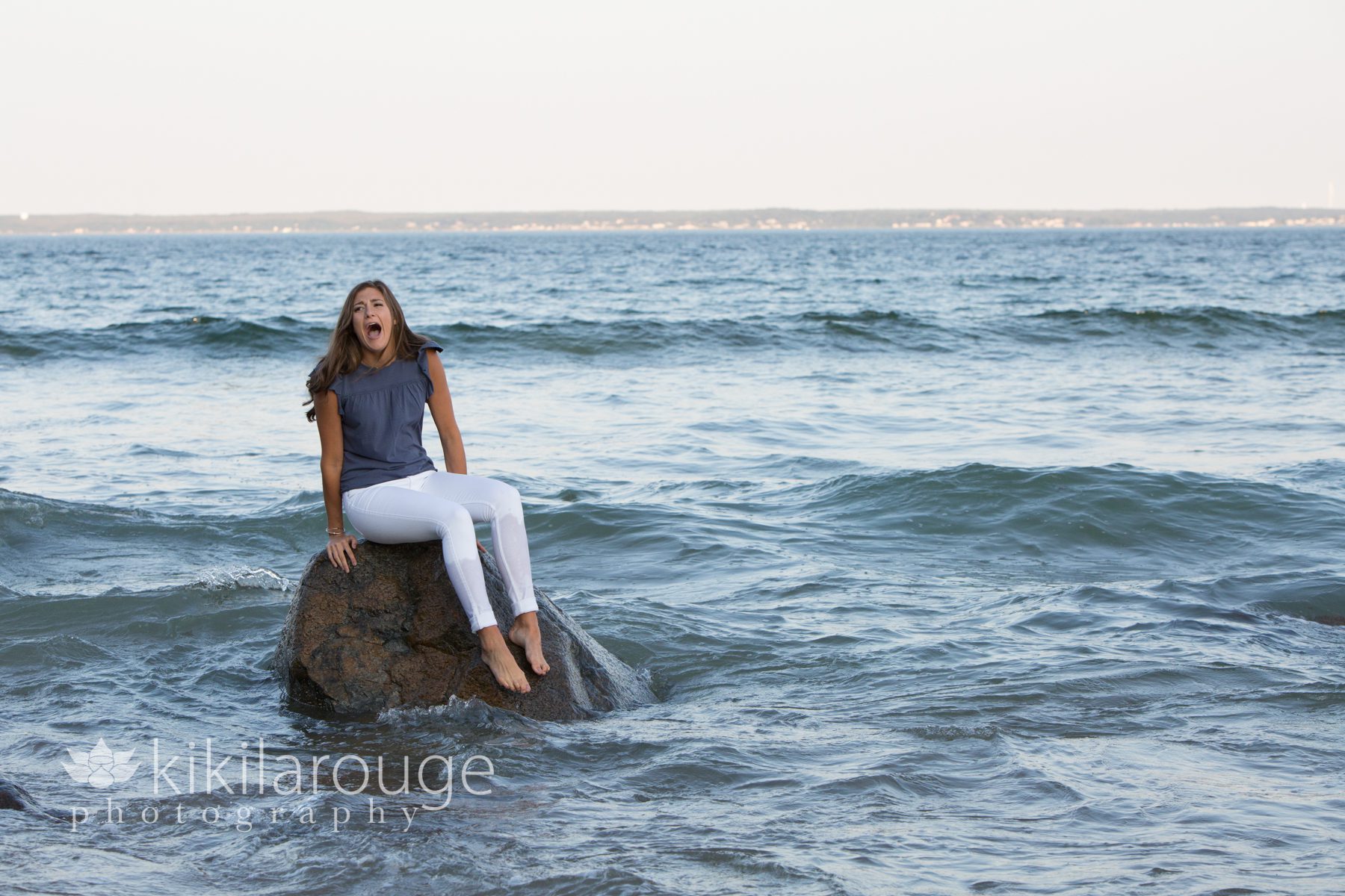 Girl sitting on a rock with waves