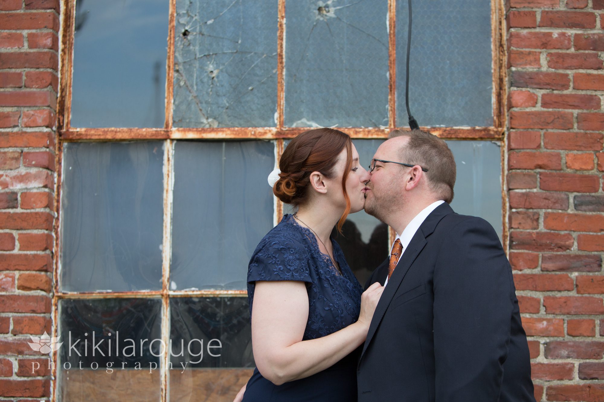Couple kissing in front of windows with reflection
