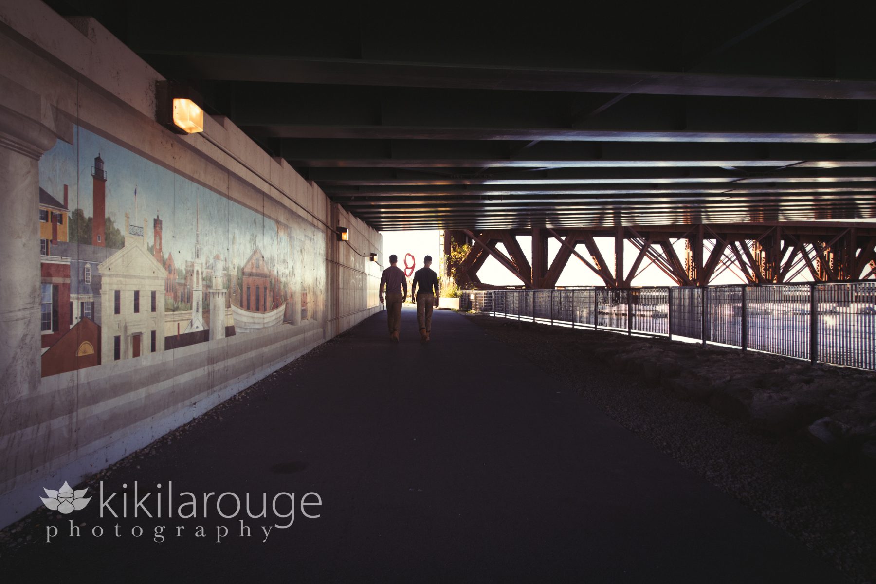 Silhouette teen brothers walking under bridge