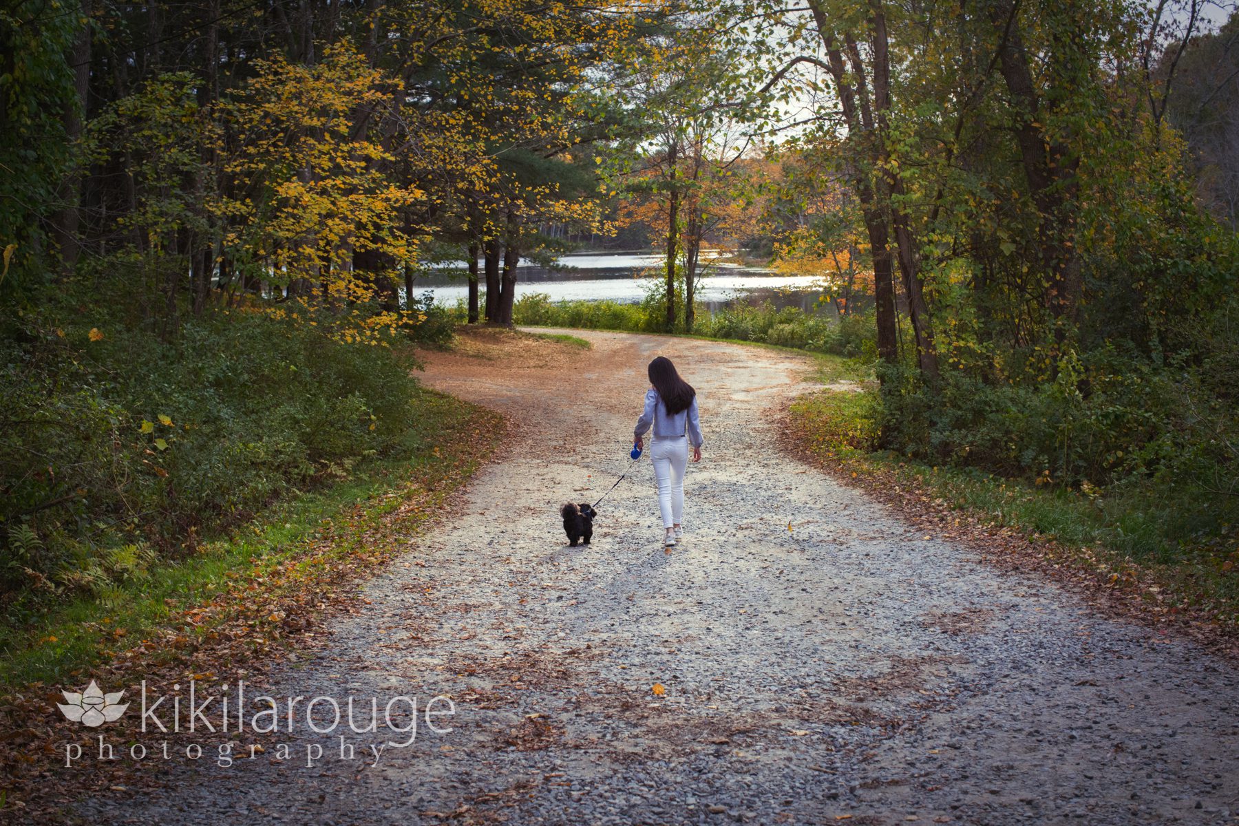 Girl walking down gravel road fall with dog