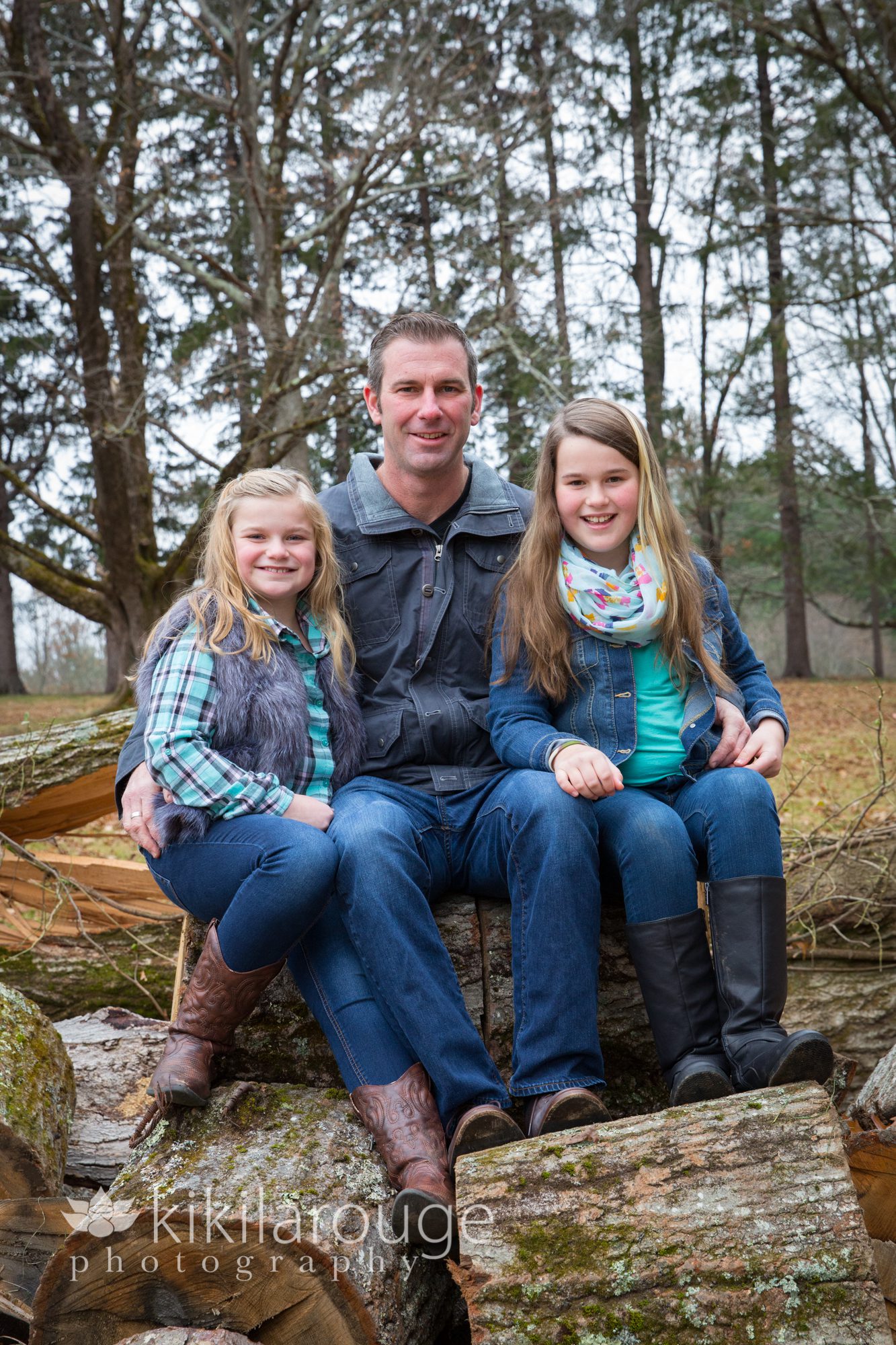 Dad sitting on log with two daughters