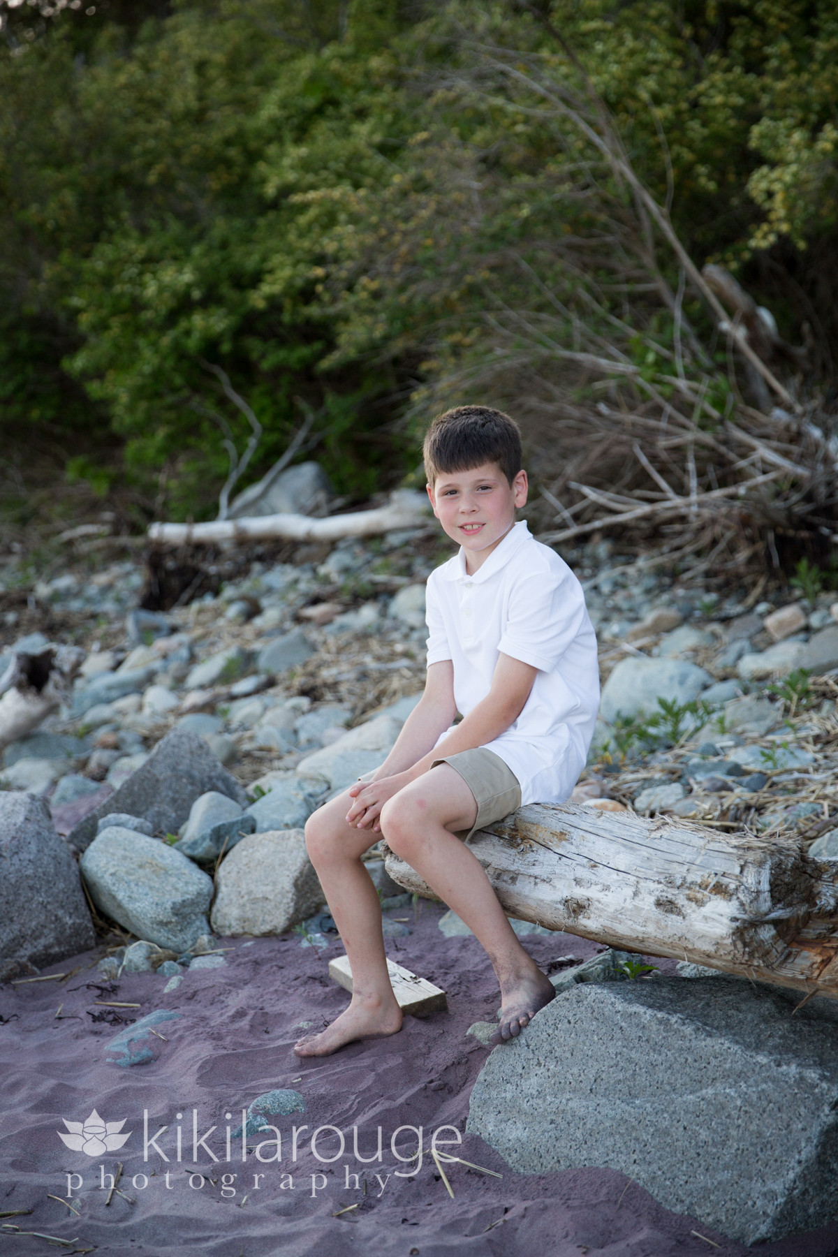 Little boy in white shirt on driftwood at beach