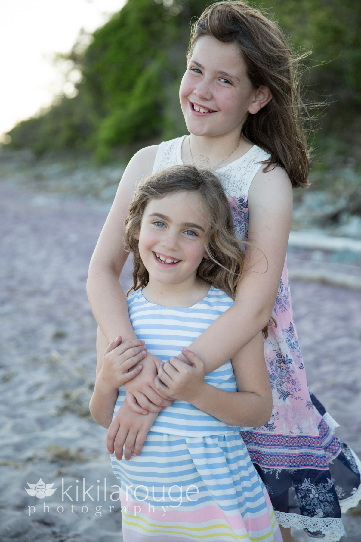 Two girls in dresses smiling at beach