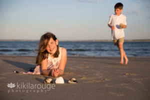 Young girl with shells at beach boy in background