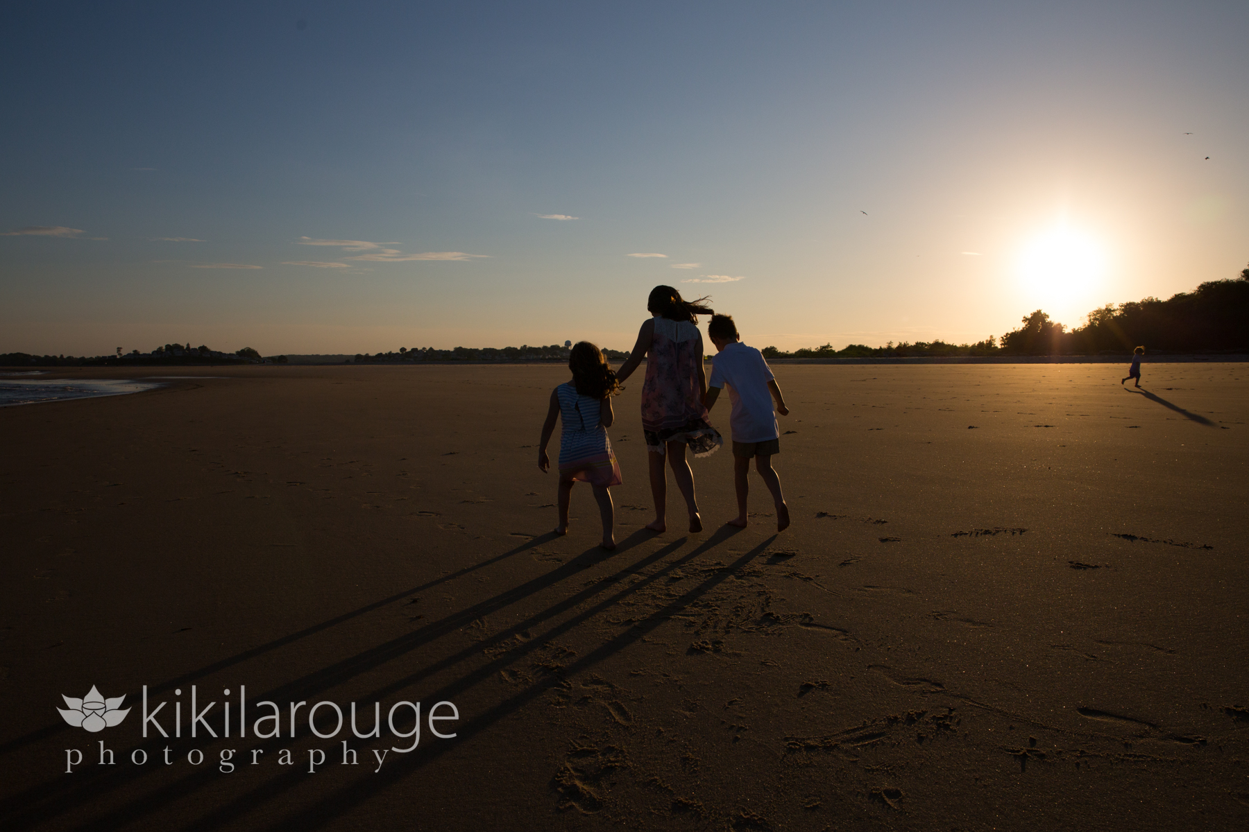 Silhouette of kids walking at sunset on beach