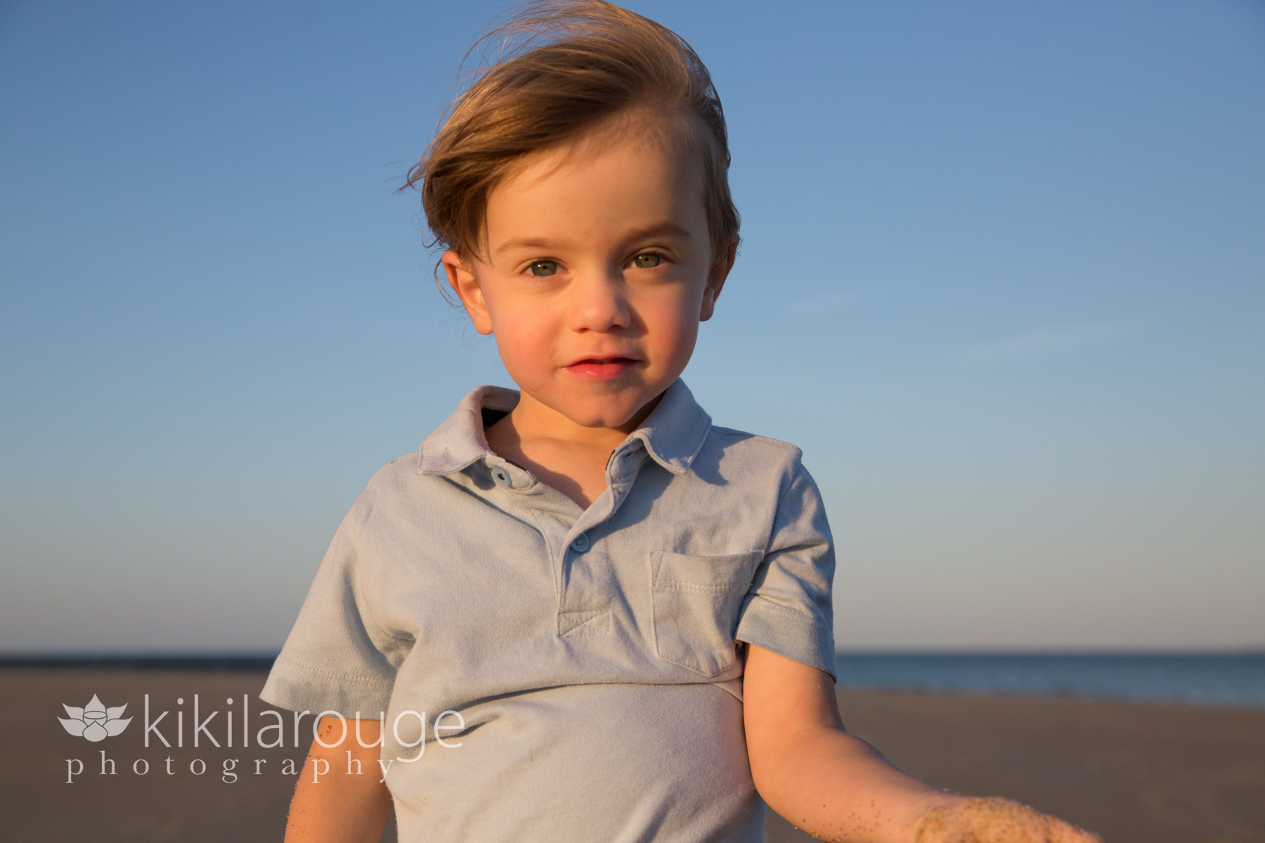 Close up of little boy in light blue shirt at beach