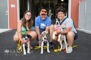 Three people with three puppies at brewery