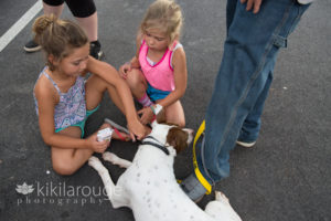 two little girls with a rescue dog sitting in parking lot