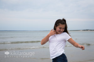 Brunette girl dancing at water's edge at beach