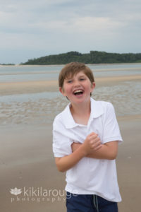 Boy in white shirt laughing at beach