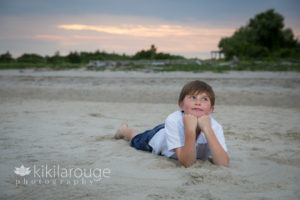 Sunset at beach with young boy sitting in sand