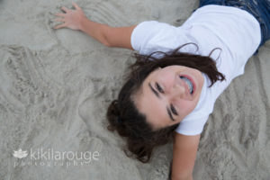Girl laying and laughing down on the sandy beach