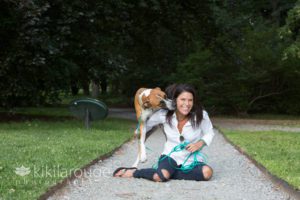 Woman in denim sitting on path with tan dog giving her kisses