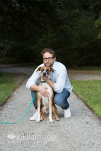 Man with jeans on path sitting with tan dog