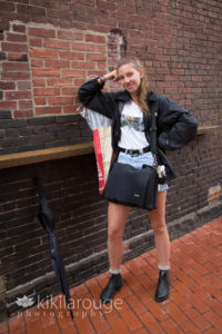 Girl leaning and smiling against brick wall