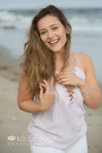 Girl at beach lilac top laughing by water