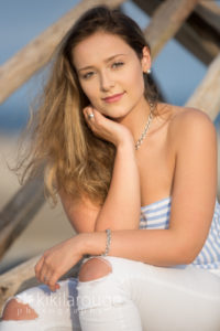 Senior portrait girl sitting on driftwood at beach