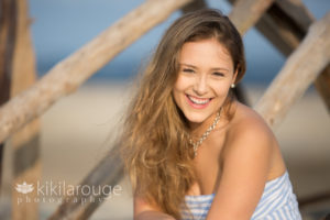Senior portrait girl sitting on driftwood at beach