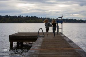 Girls running down dock at sunset