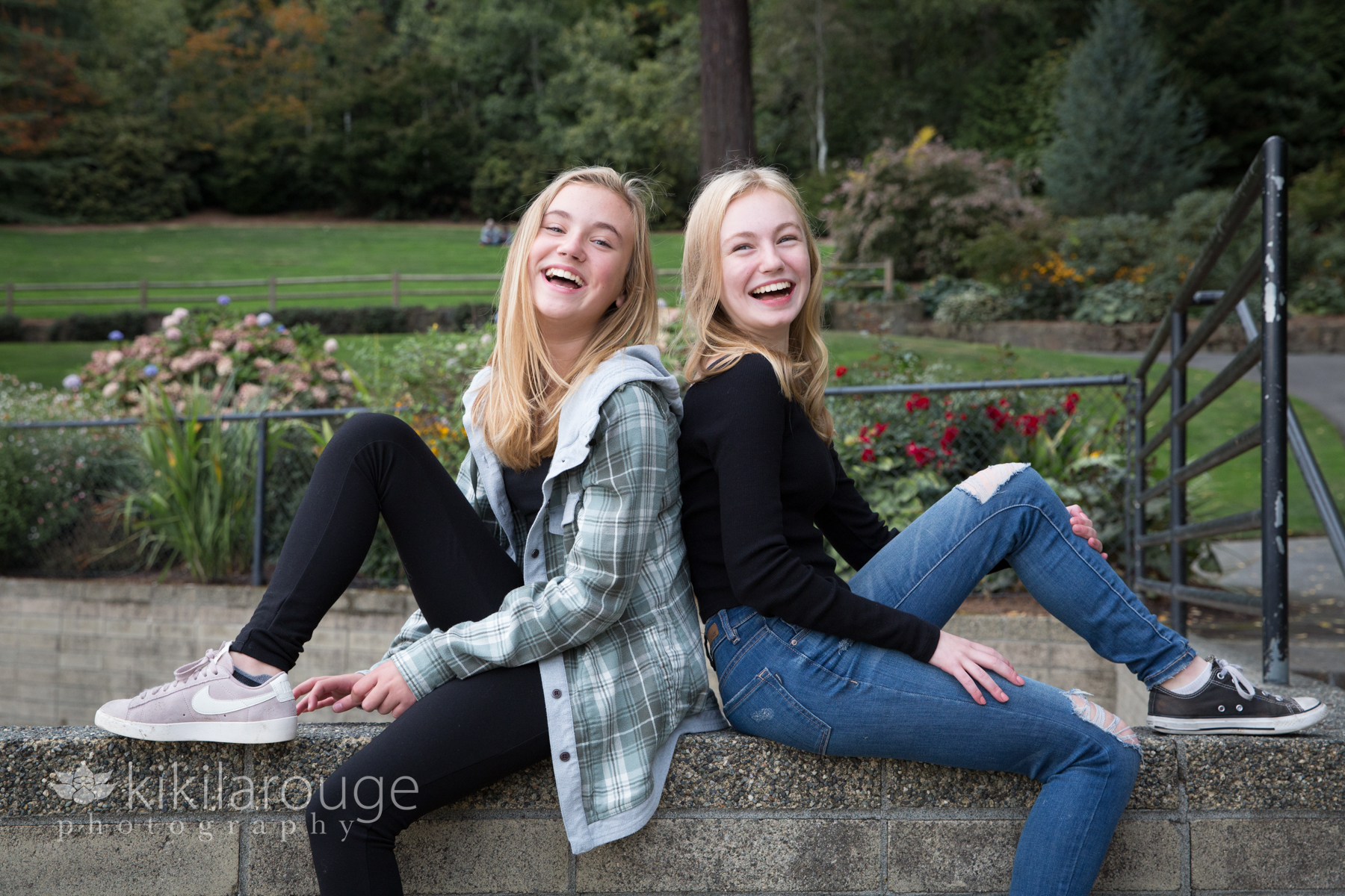 Two sister sitting on cement wall laughing Seattle
