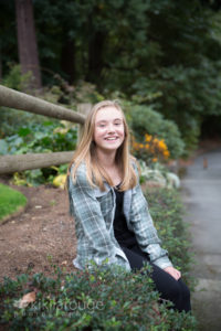 Young girl sitting on rock wall with flowers