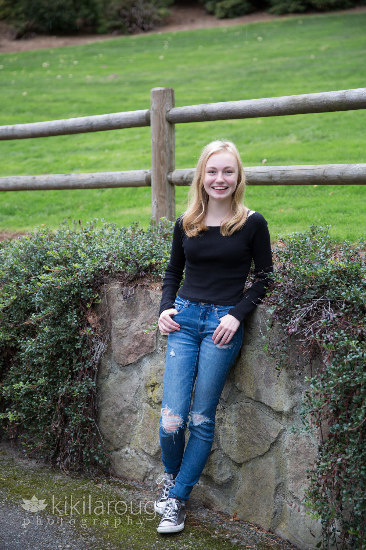 Young girl leaning on stone wall in denim jeans