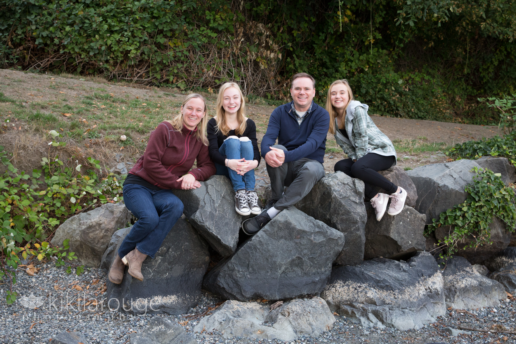 Family portrait sitting on rocks at water's edge