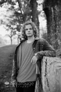 Teen boy in denim jacket leaning on stone wall