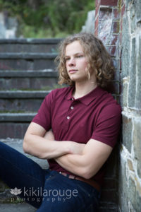Boy in cranberry polo sitting on stone steps