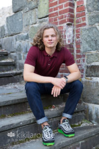Boy in cranberry polo sitting on stone steps
