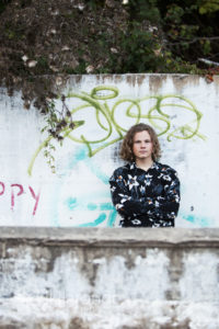Teen boy leaning on graffiti wall