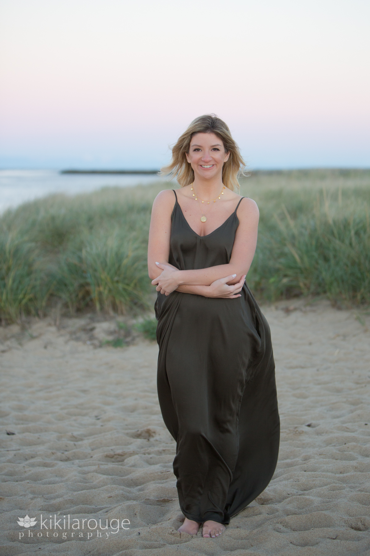Woman on windy night on beach with dunes green flowing dress