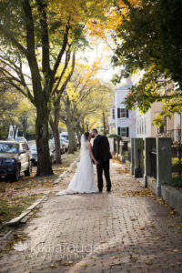 Married couple kissing on Fall street with sun flare